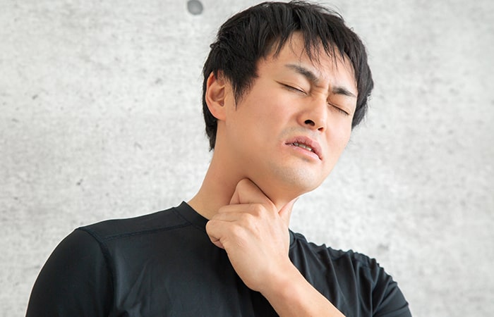 咽頭痛/喉の痛みがあり辛そうにしている男性の写真